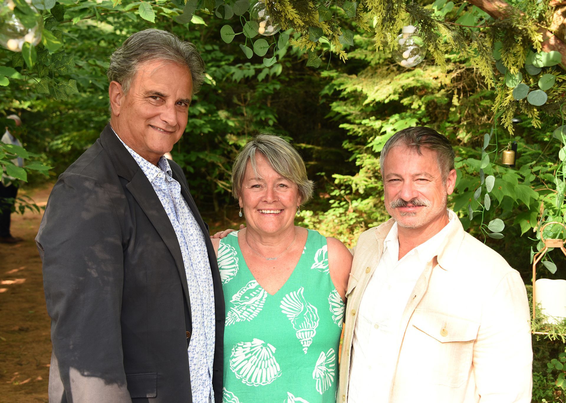 Three people smiling, standing outdoors. 