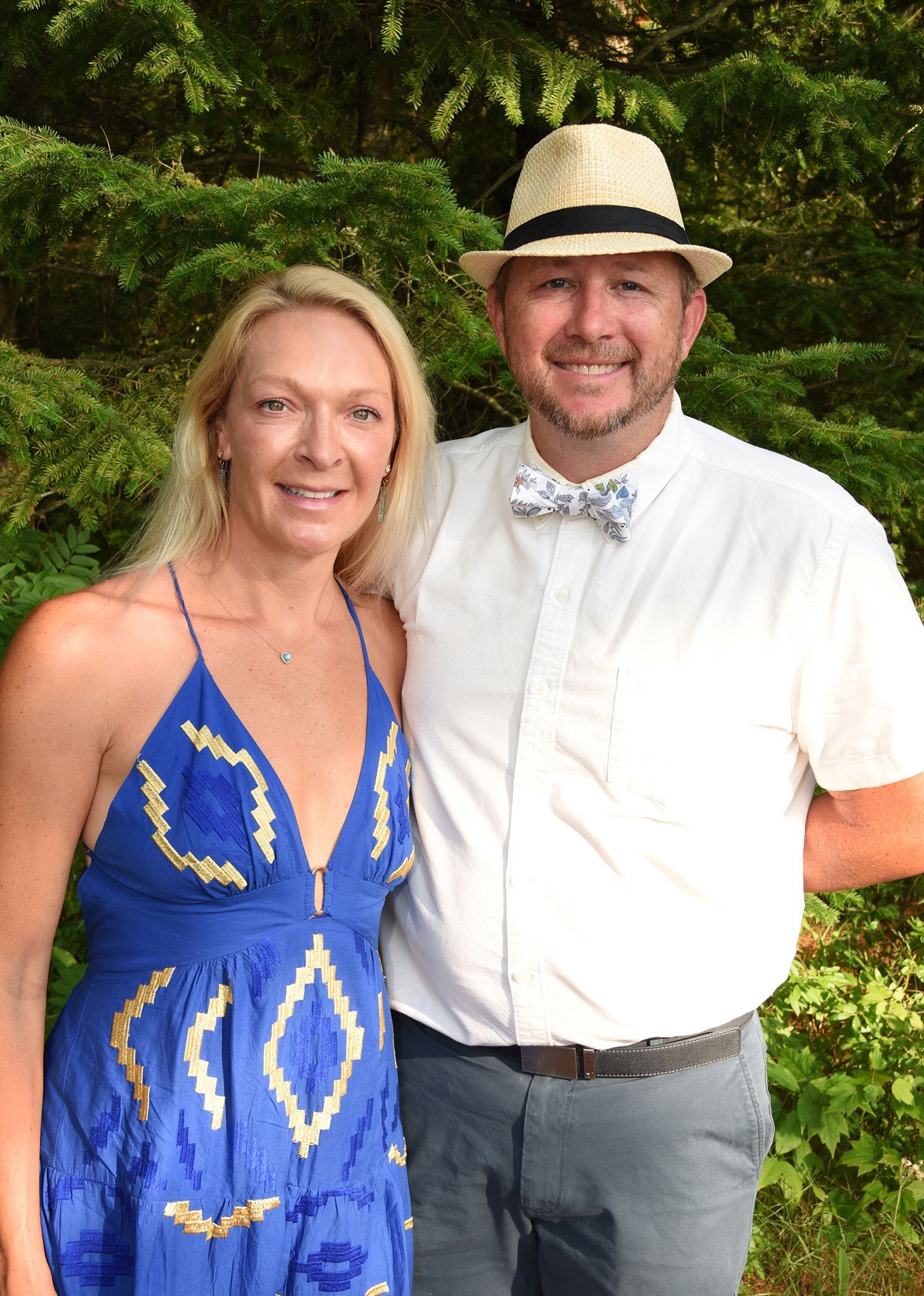 Woman and man in summer attire pose outdoors.