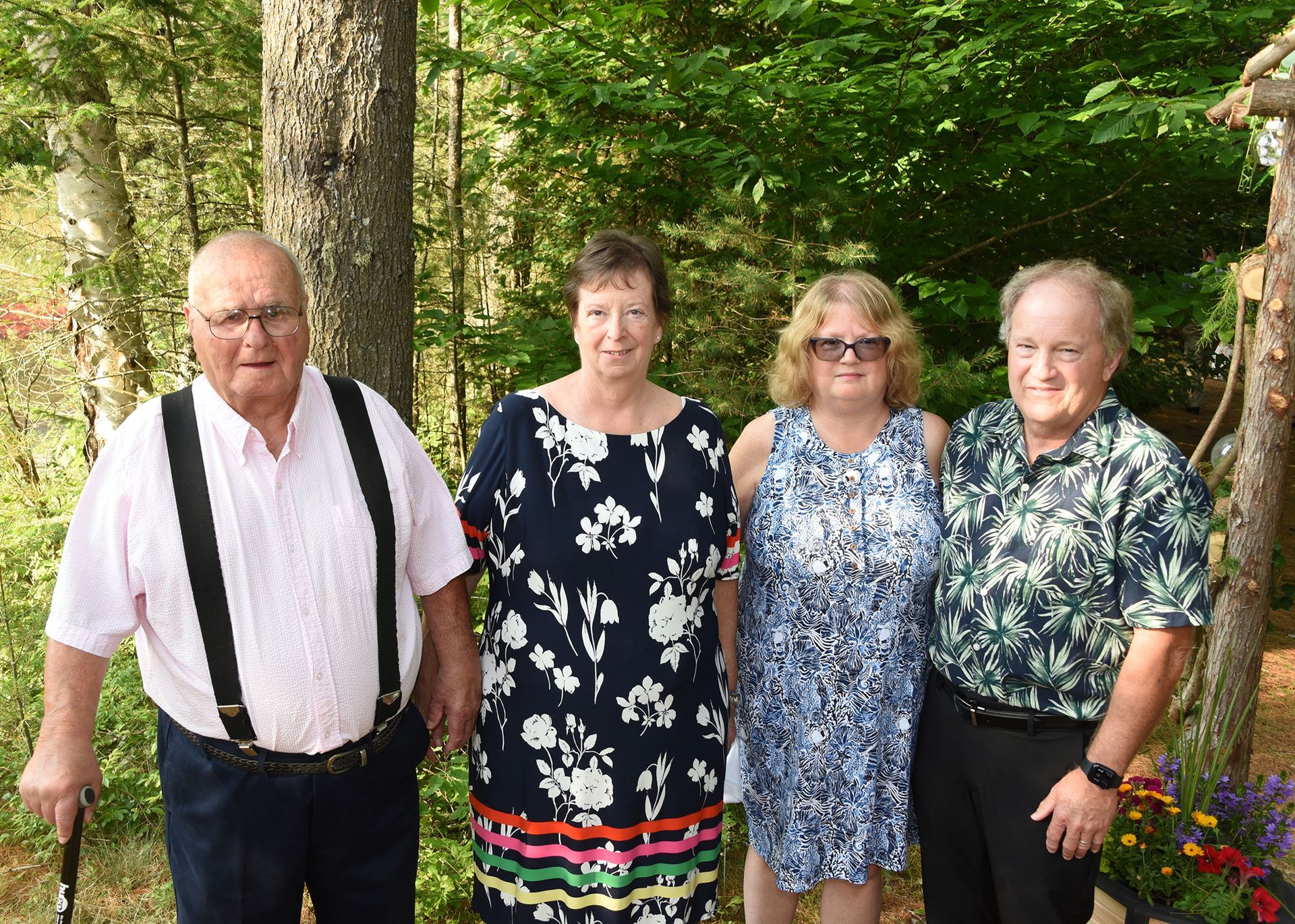 Four people standing outdoors: two men and two women. They are smiling in front of a backdrop of trees.