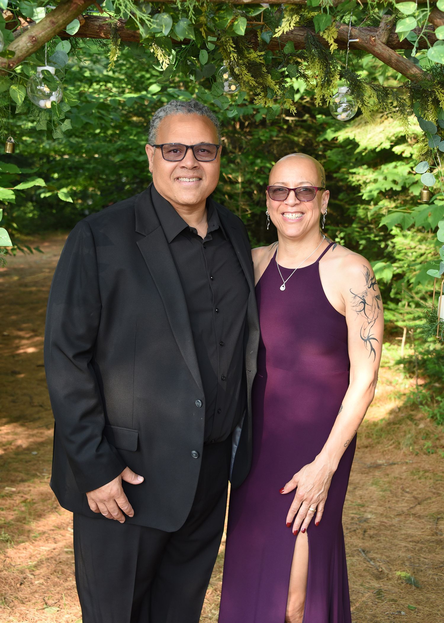 A smiling Black couple poses outdoors.