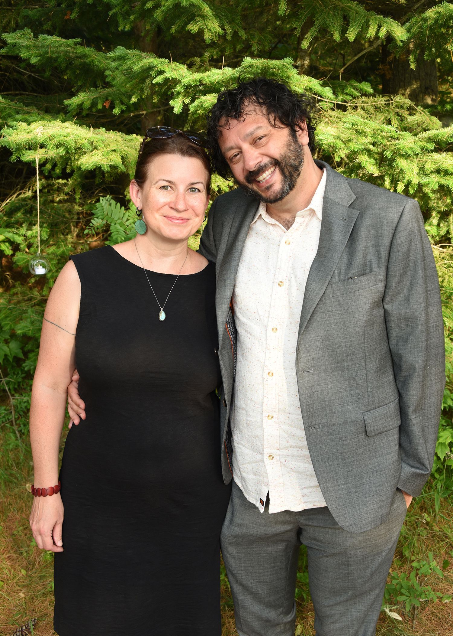 A woman and a man smiling and embracing outdoors.