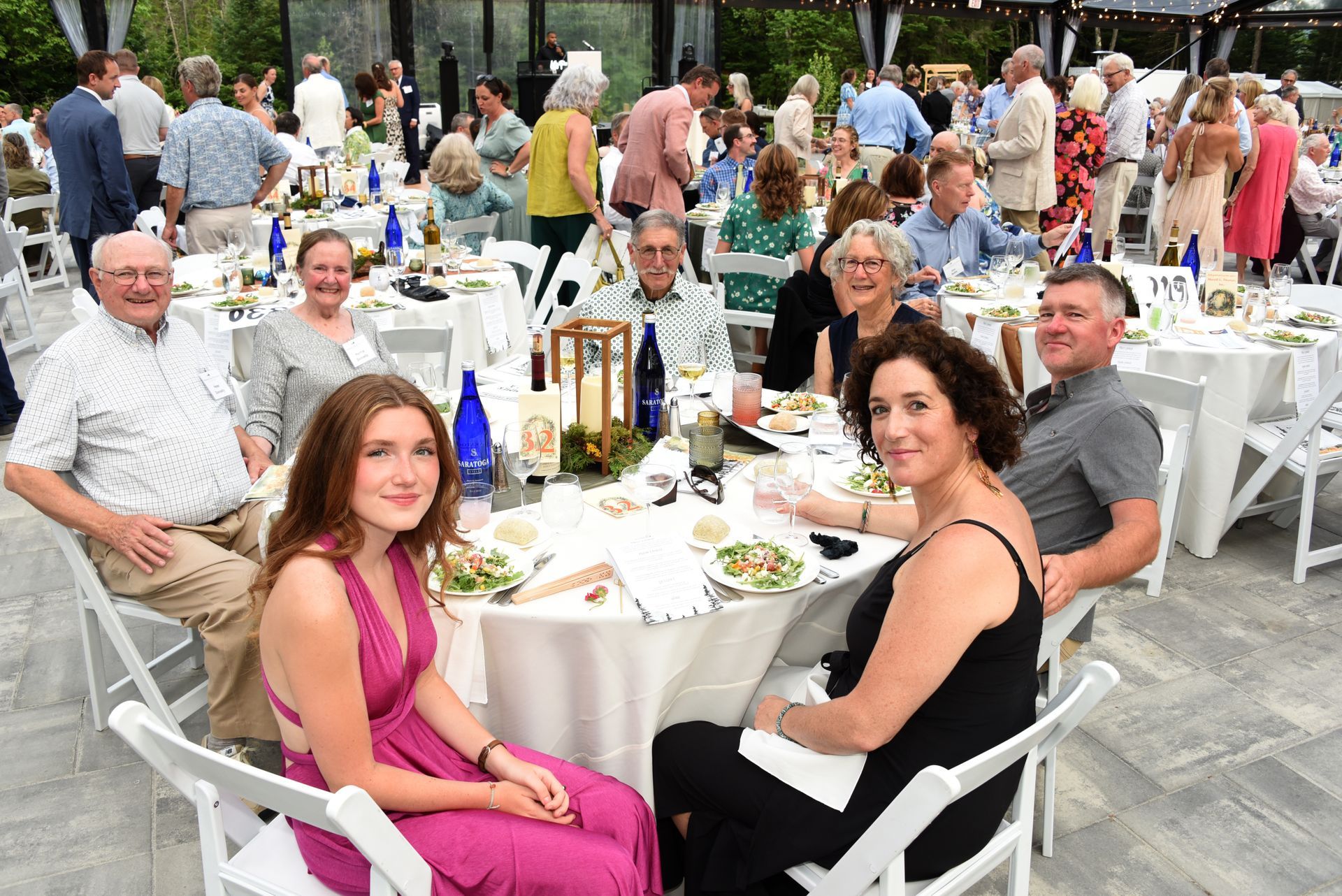 A group of people seated at a round table, some smiling at the camera.