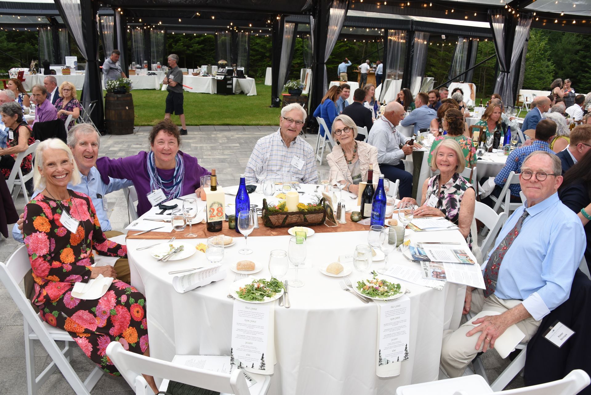A group of people seated around a table at an outdoor event. 