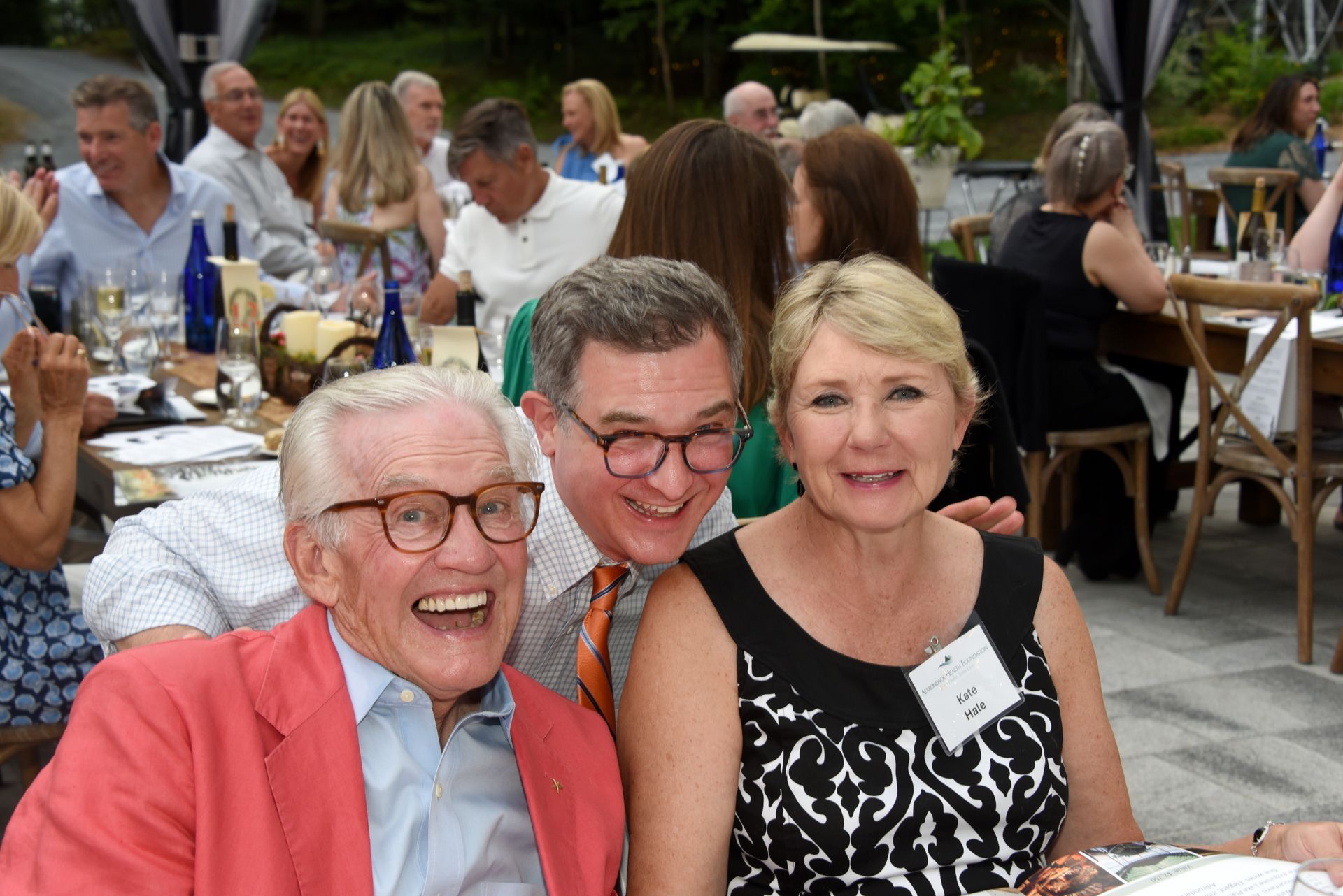 Three smiling people at an outdoor event.