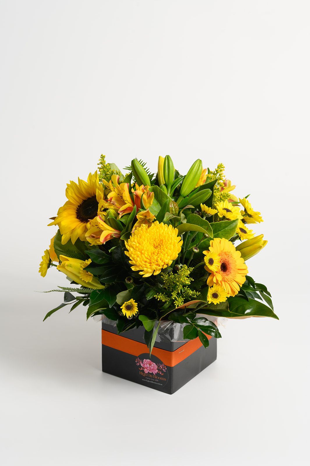 Floral arrangement in a black and orange box, featuring sunflowers, lilies, and yellow gerbera daisies.