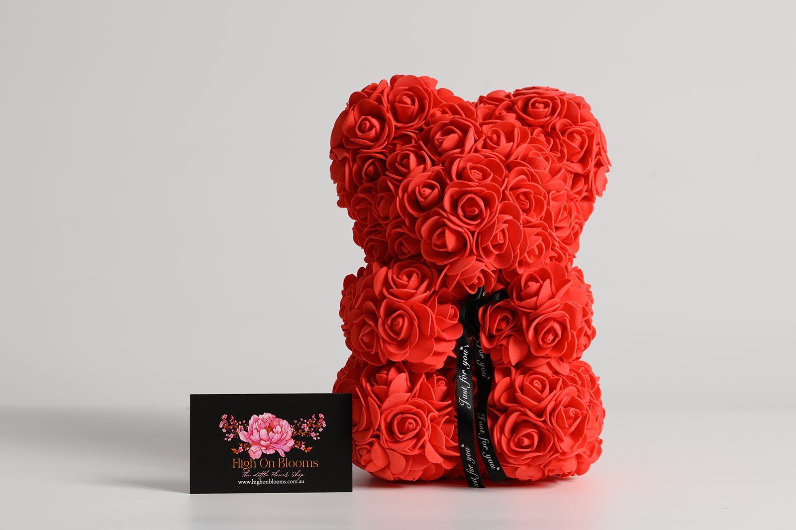Red rose bear with a business card in front.
