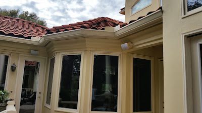 Beige house exterior with red tile roof and bay windows.
