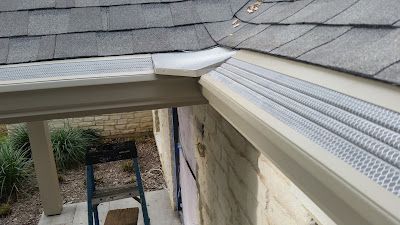Gutter with mesh screen installed on a roof, protecting against debris.