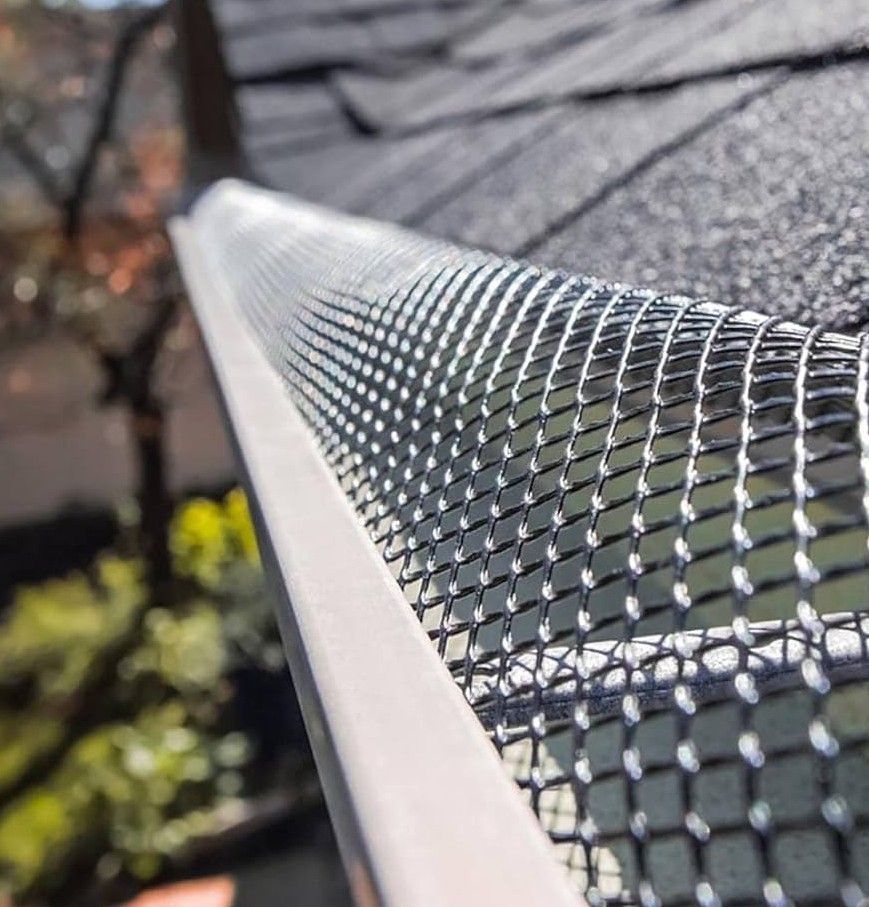 Brown shingled roof with white gutters and brick facade.