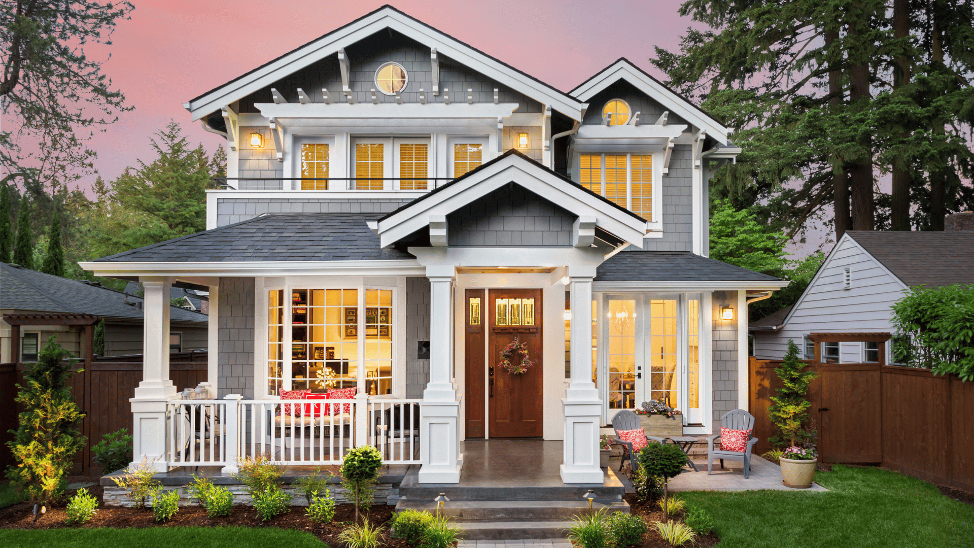 A large house with a large porch is lit up at night.