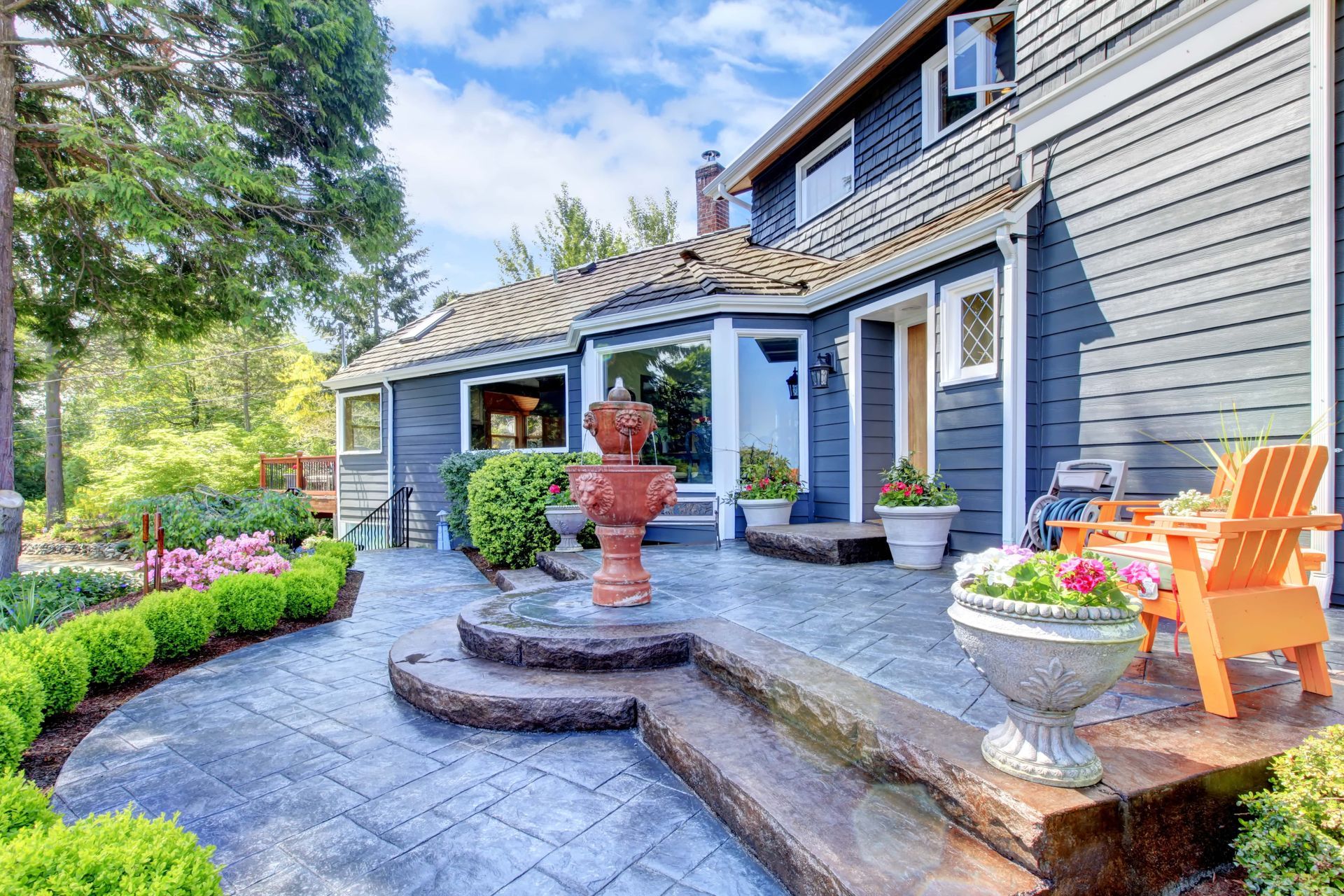 A large house with a patio and chairs in front of it.