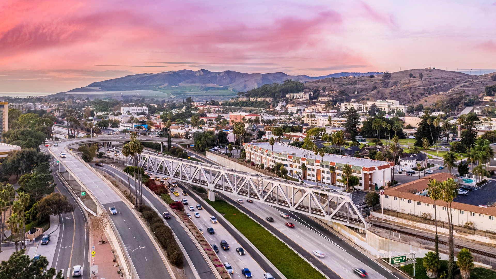 An aerial view of a highway going through a city at sunset.