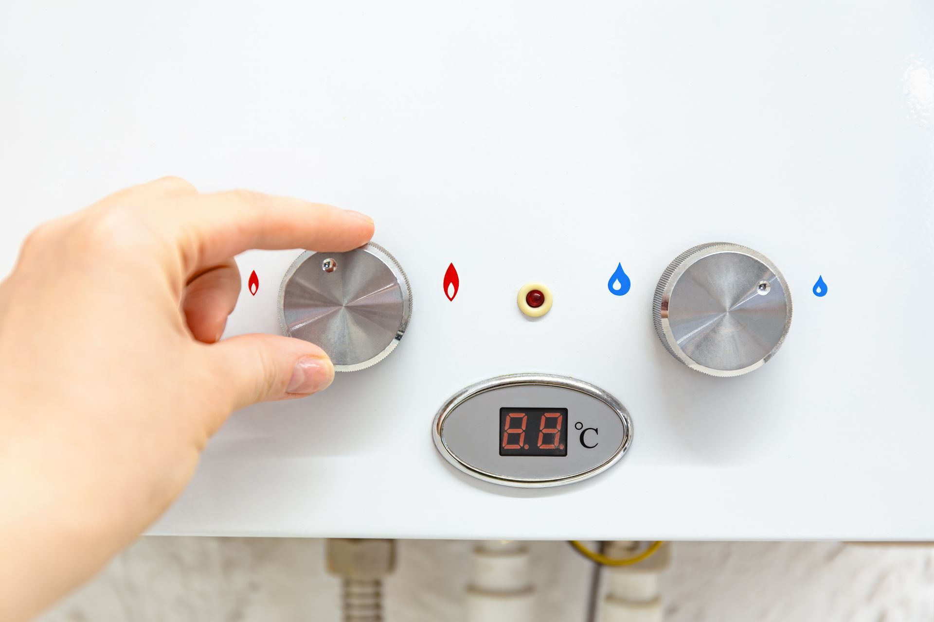 A hand adjusts the dial on a white gas water heater with a digital temperature display.