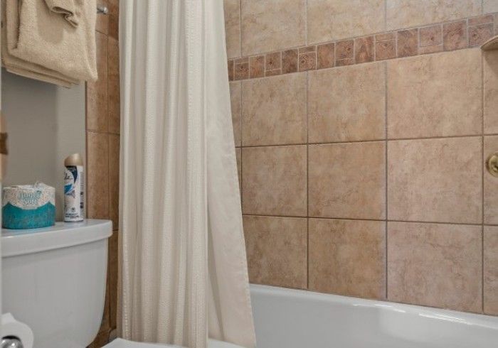 A bathroom with a toilet , bathtub and shower curtain.
