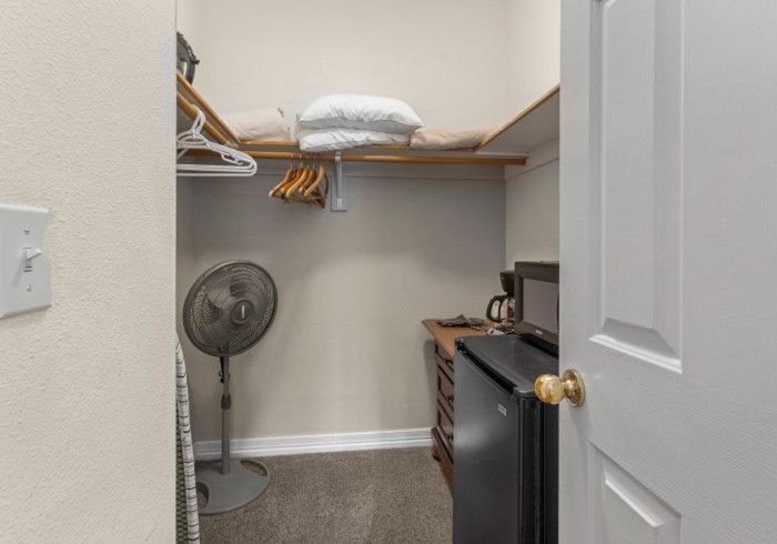 A walk in closet with a fan , refrigerator , microwave and coffee maker.