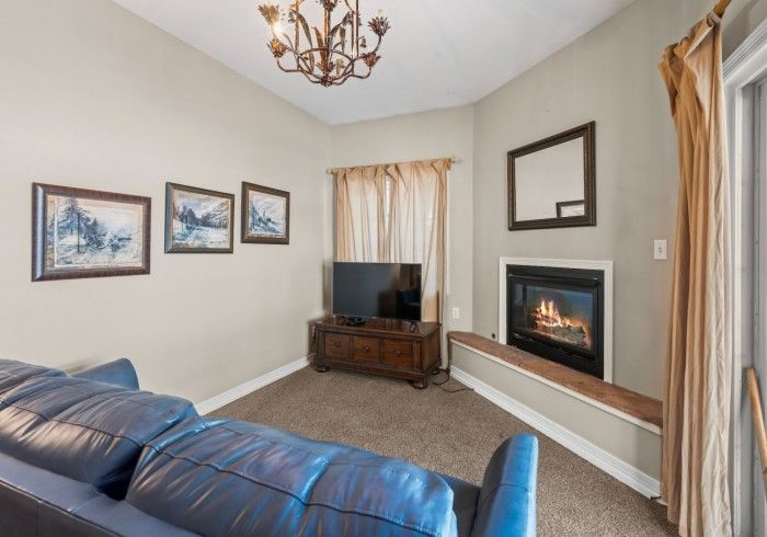 A living room with a fireplace , couch , television and chandelier.
