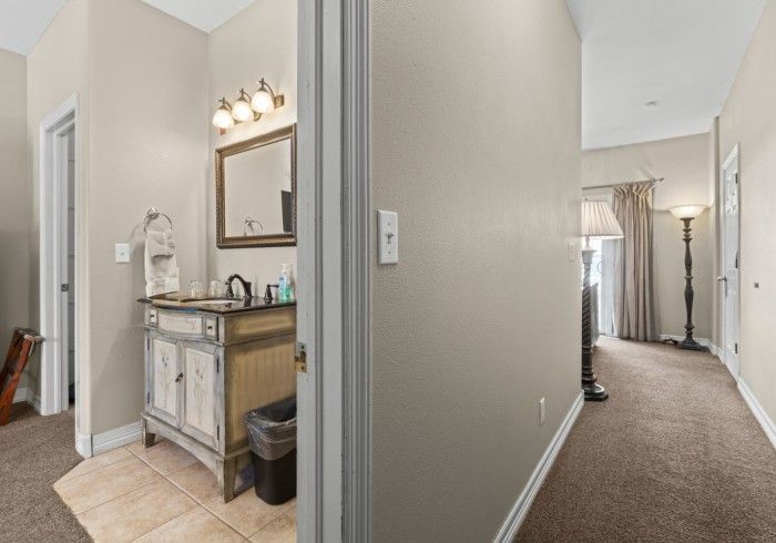 A bathroom with a sink , mirror , and trash can.