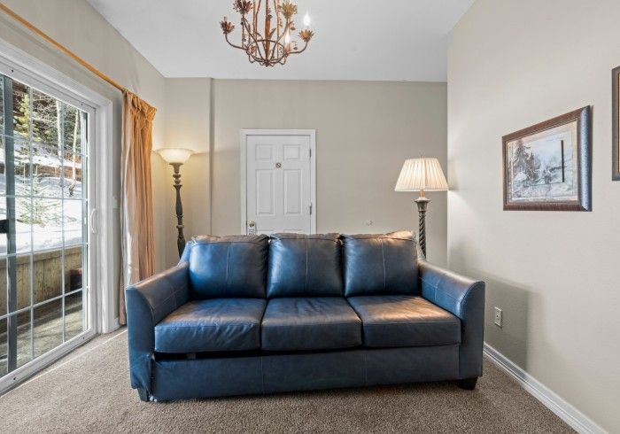 A living room with a blue couch and a lamp.