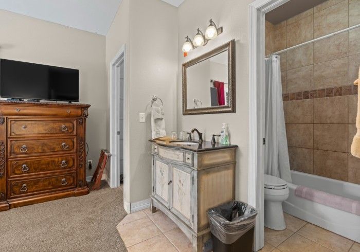 A bathroom with a sink , toilet , mirror and television.