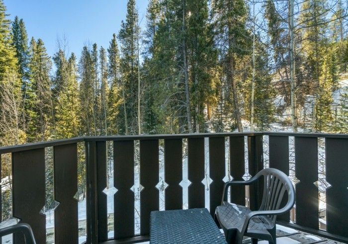 A balcony with a table and chairs overlooking a forest.