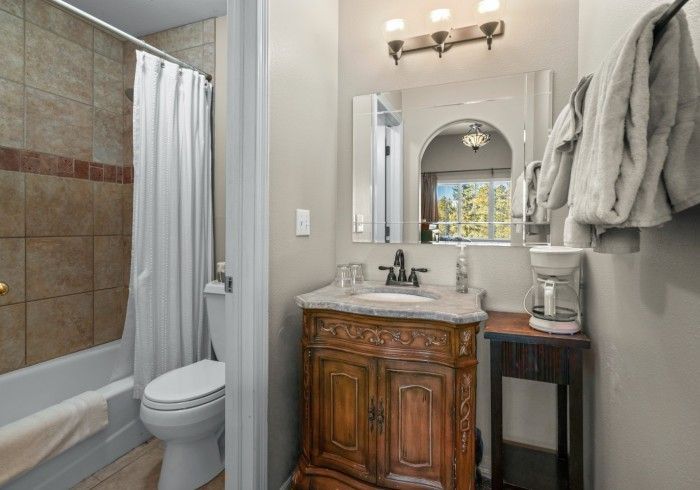 A bathroom with a toilet , sink , mirror and shower curtain.