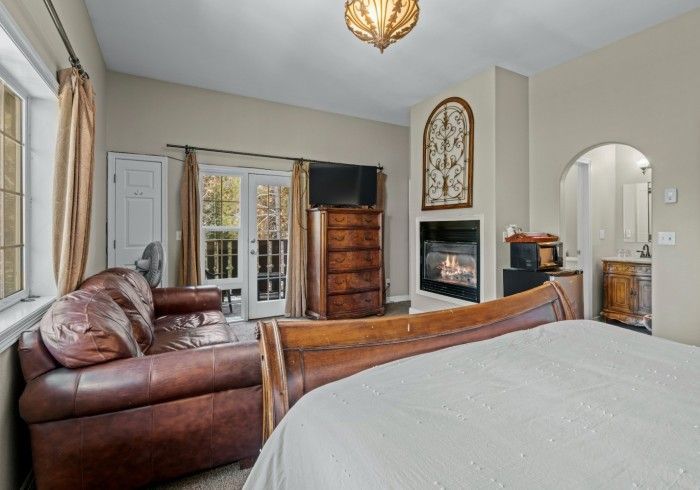 A bedroom with a bed , couch , fireplace and television.