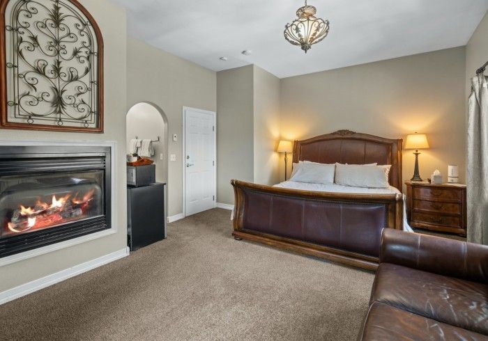 A bedroom with a king size bed and a fireplace.