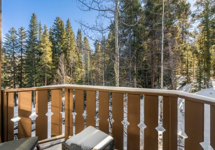 A balcony overlooking a forest with a chair on it