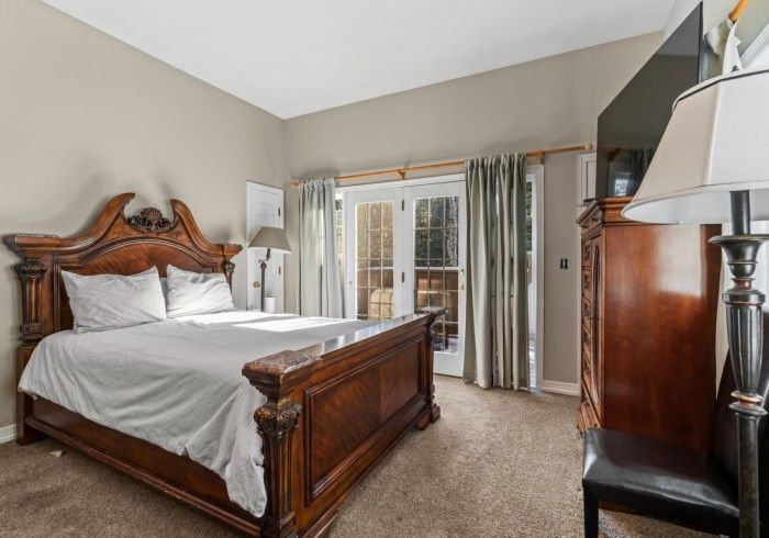 A bedroom with a king size bed , dresser , lamp and television.