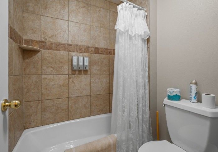 A bathroom with a tub , toilet and shower curtain.
