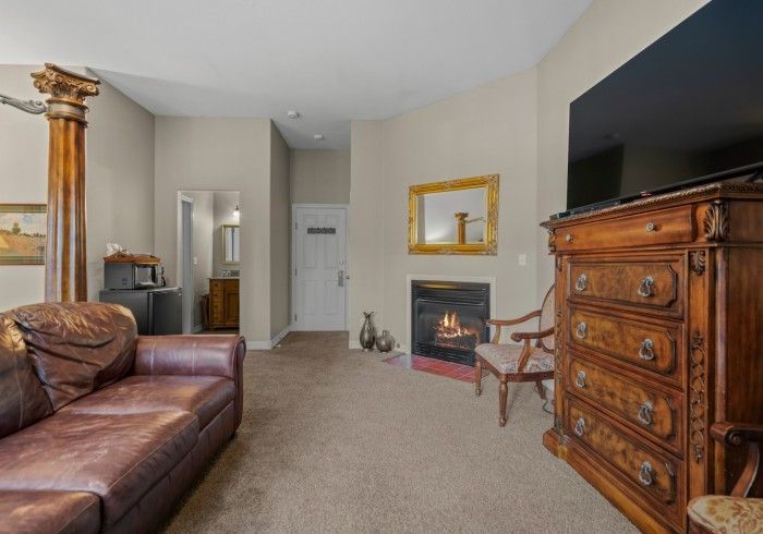 A living room with a couch , dresser , television and fireplace.
