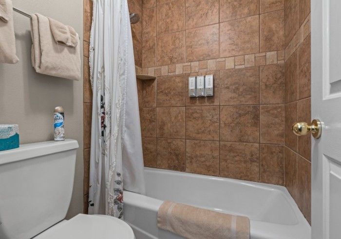 A bathroom with a toilet , tub , shower and towels.