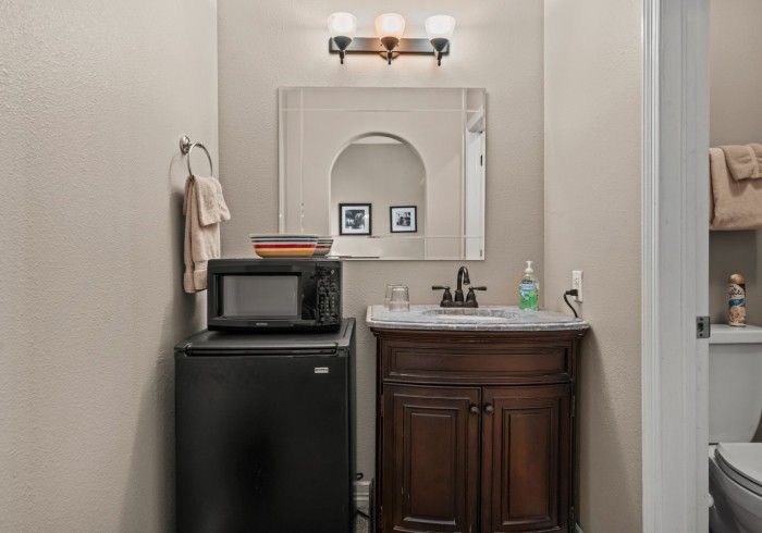 A bathroom with a sink , microwave , and toilet.