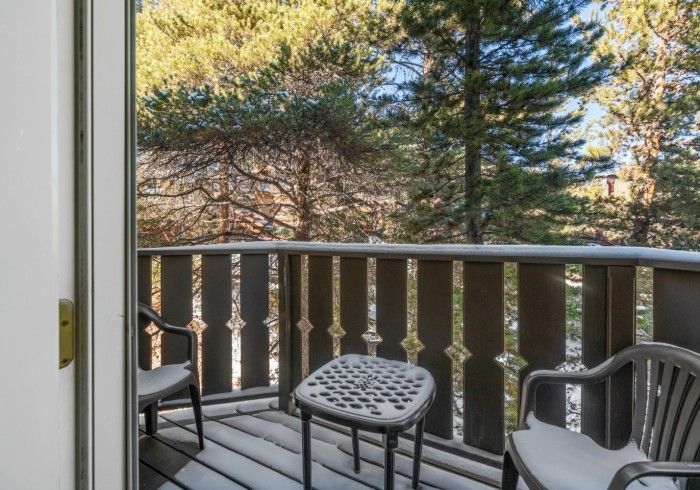 A balcony with a table and chairs and trees in the background