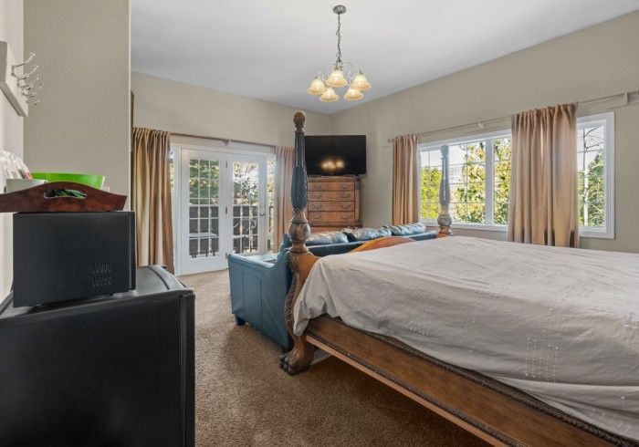 A bedroom with a king size bed , couch , television and a refrigerator.