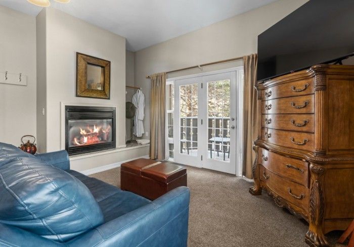 A living room with a couch , fireplace , dresser and television.
