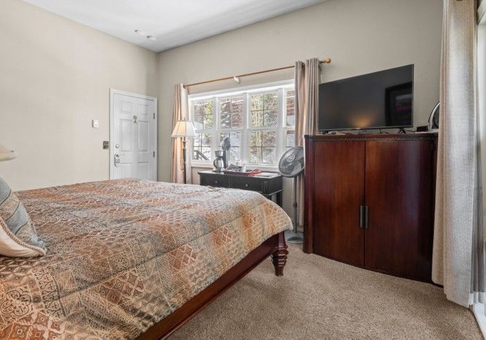 A bedroom with a bed , television , desk and window.