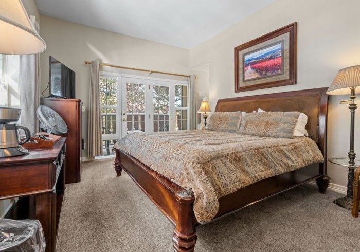 A bedroom with a king size bed , a desk , lamps and a television.