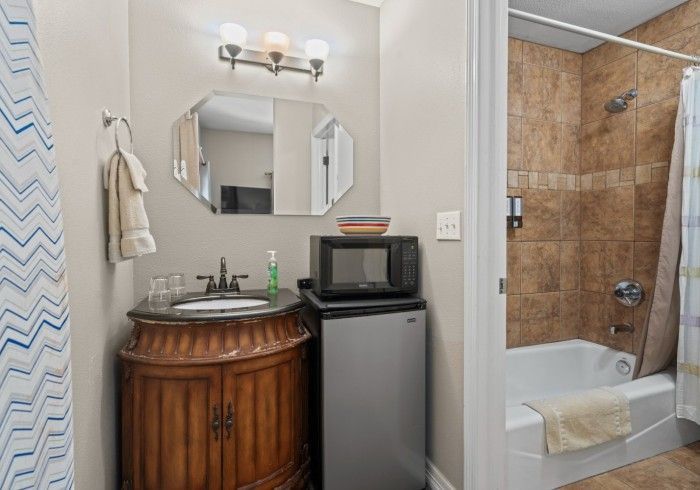 A bathroom with a sink , microwave , and shower.