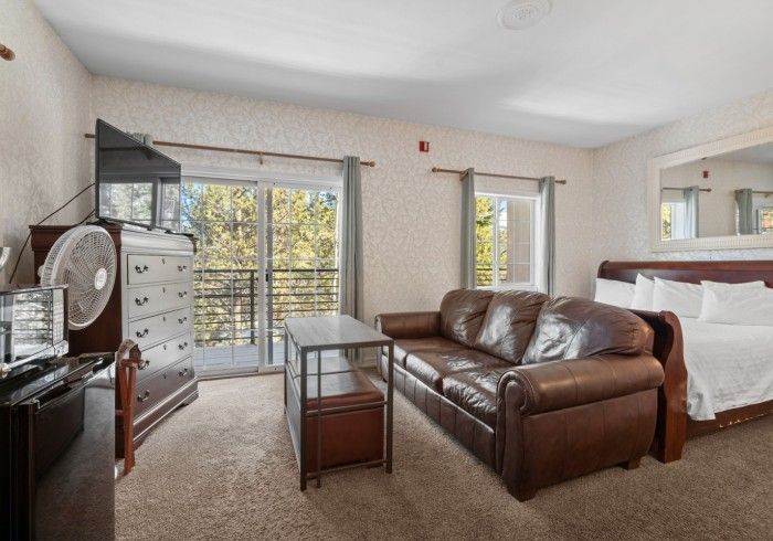 A living room with a couch , table , television and a bed.