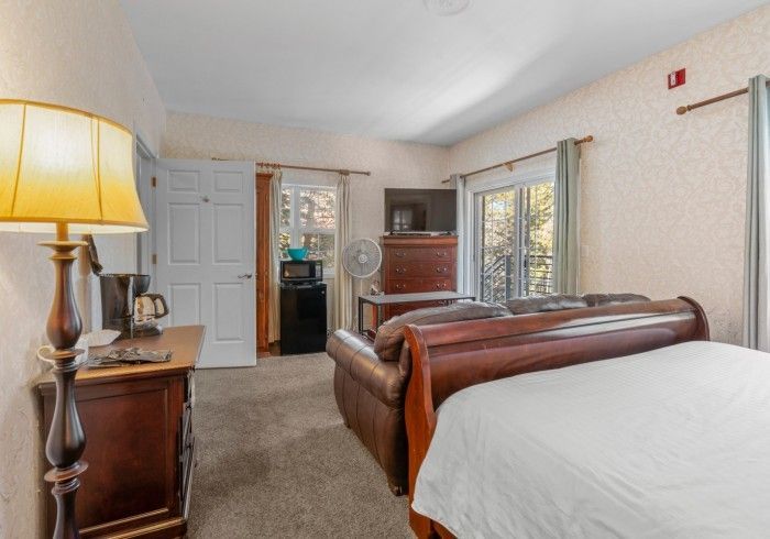 A hotel room with two beds , a couch , a lamp and a dresser.