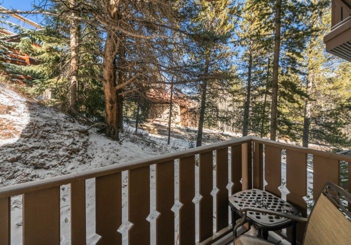 A balcony with a table and chairs overlooking a snowy forest.
