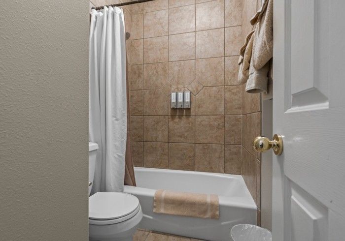 A bathroom with a toilet , tub and shower.