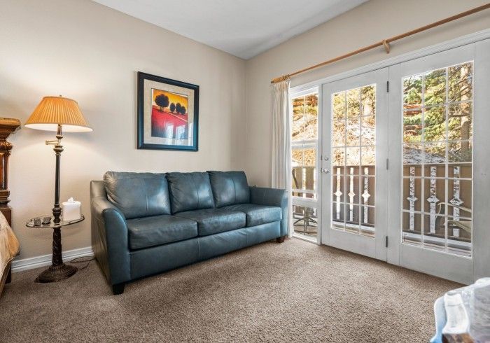 A living room with a couch , lamp , and sliding glass doors.
