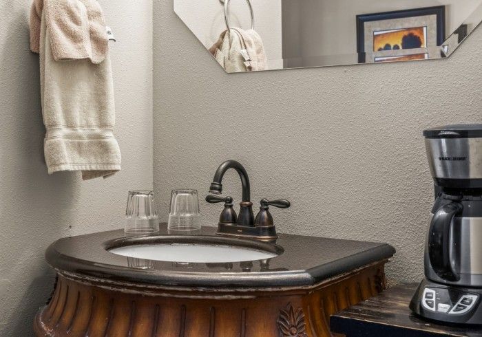 A bathroom with a sink , coffee maker and mirror.
