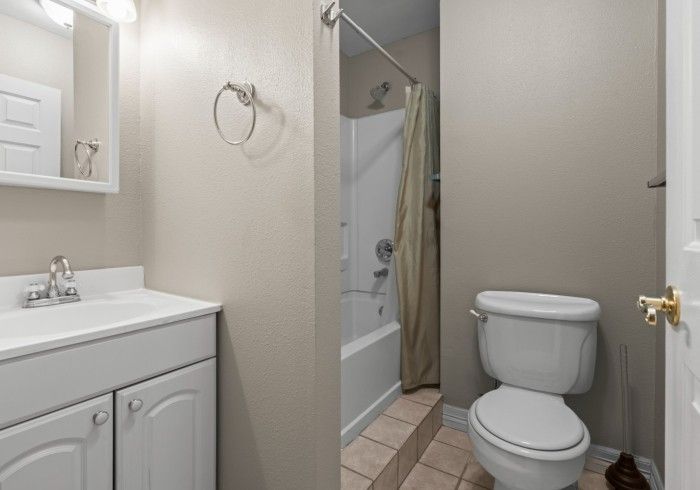 A bathroom with a toilet , sink and shower.