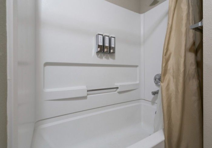A bathroom with a bathtub , shower , and soap dispensers.