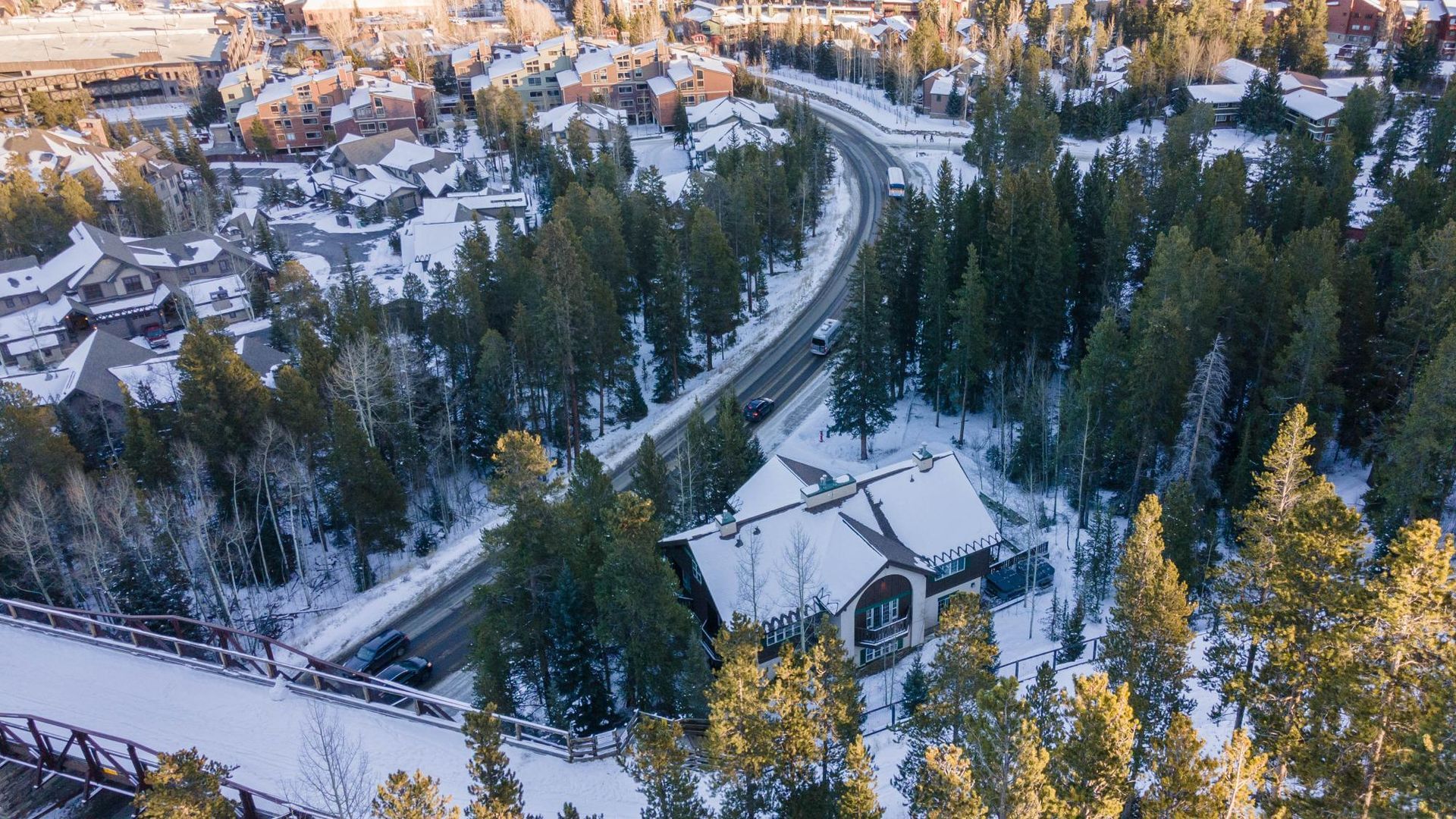 An aerial view of a snowy forest with a road going through it.