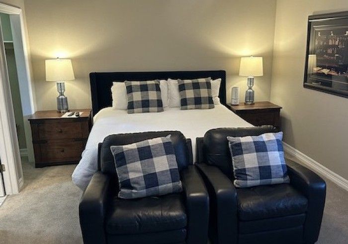 A bedroom with a king size bed and two chairs