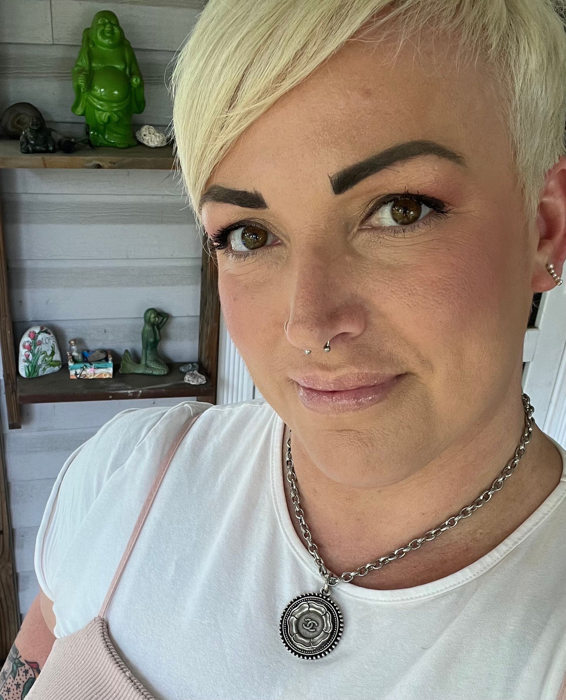 A close up of a woman wearing a necklace and a white shirt.